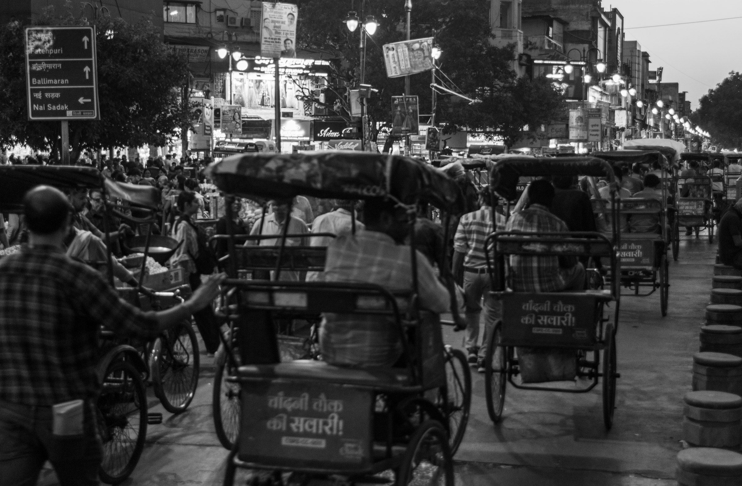 Cycle rickshaws on a busy Chandni Chowk street at dusk
