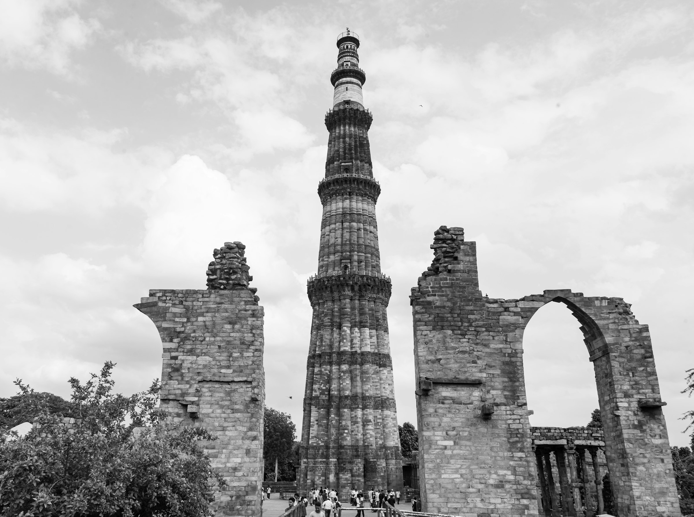 The Qutub Minar with ruins around it, in black and white
